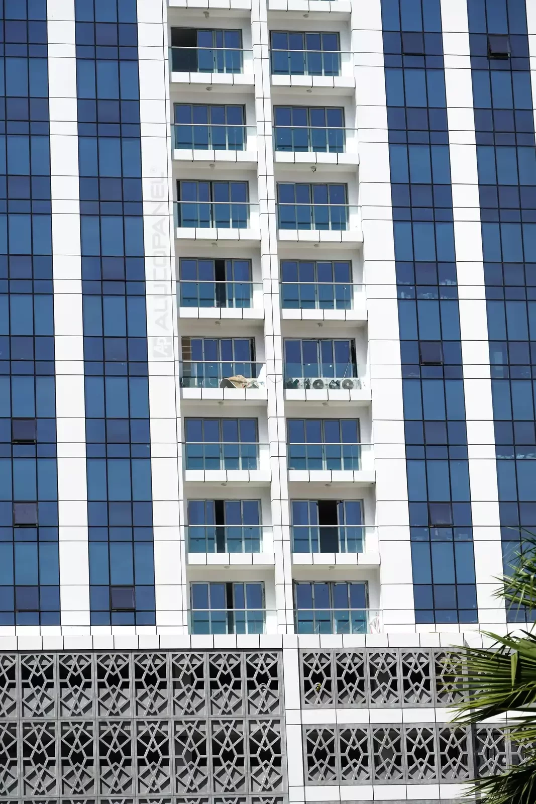White ALUCOPANEL facade with glazing and rooftop mashrabiya screen at Ajman Res Tower